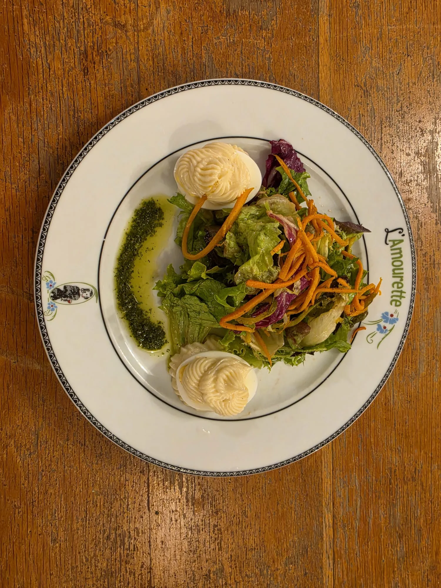 Salade verte accompagnée de deux œufs garnis sur une assiette de L’Amourette
